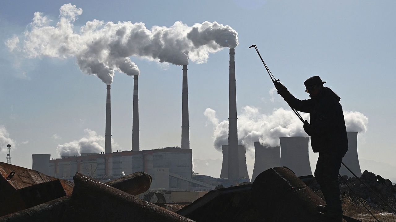 A worker uses a torch to cut steel pipes near the coal-powered Datang International Zhangjiakou Power Station