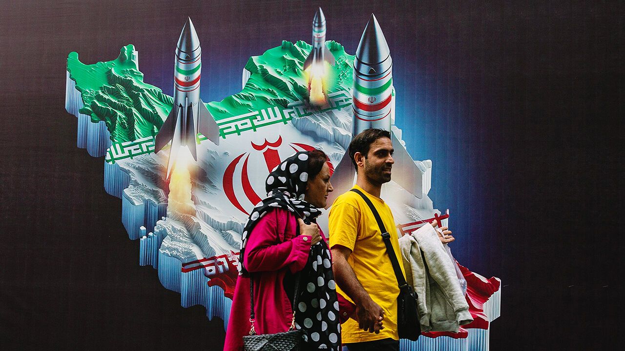 People walk past a mural depicting Iranian missiles in Tehran