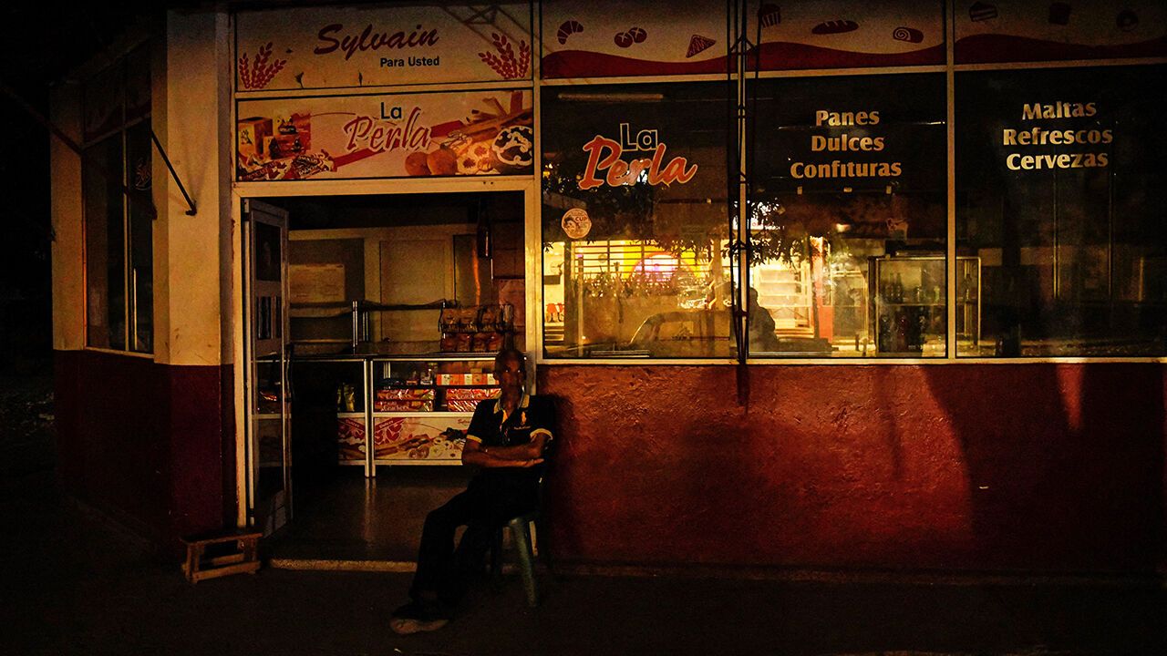 A caretaker sits outside a shop during a blackout in Havana, Cuba