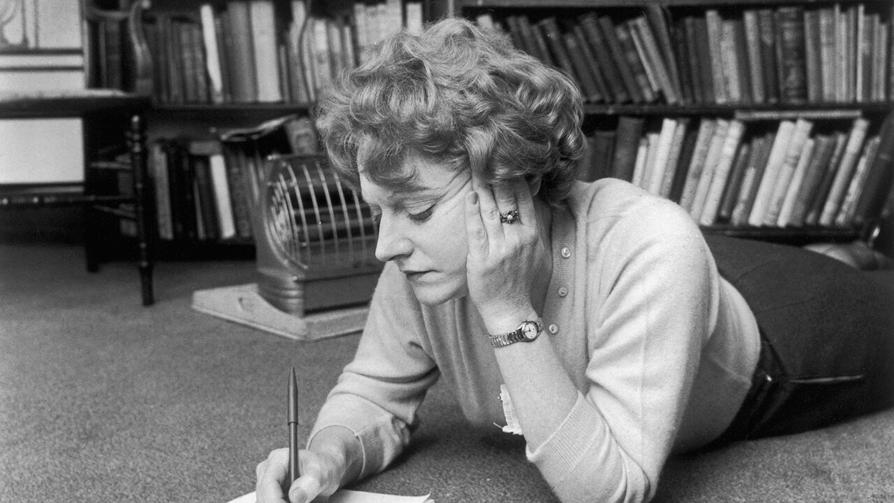 Muriel Spark lies on the floor while writing in 1960