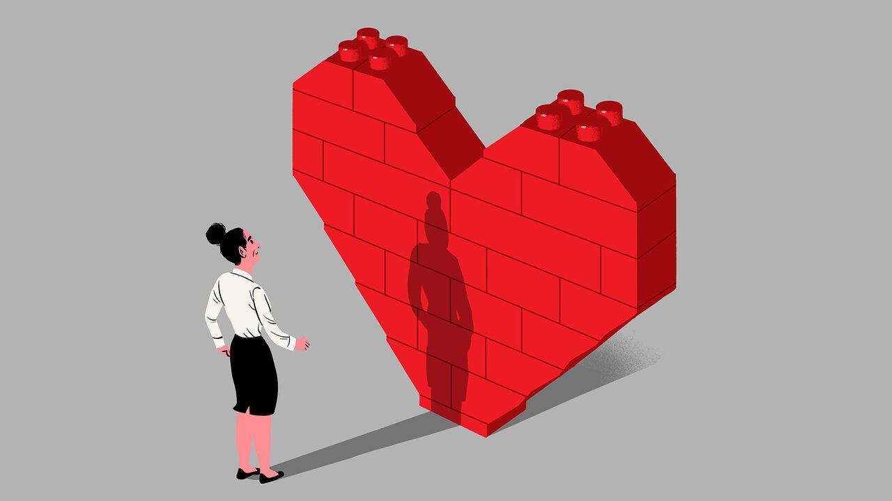 An office worker looking at a big wall made of Lego bricks, in the shape of a heart.
